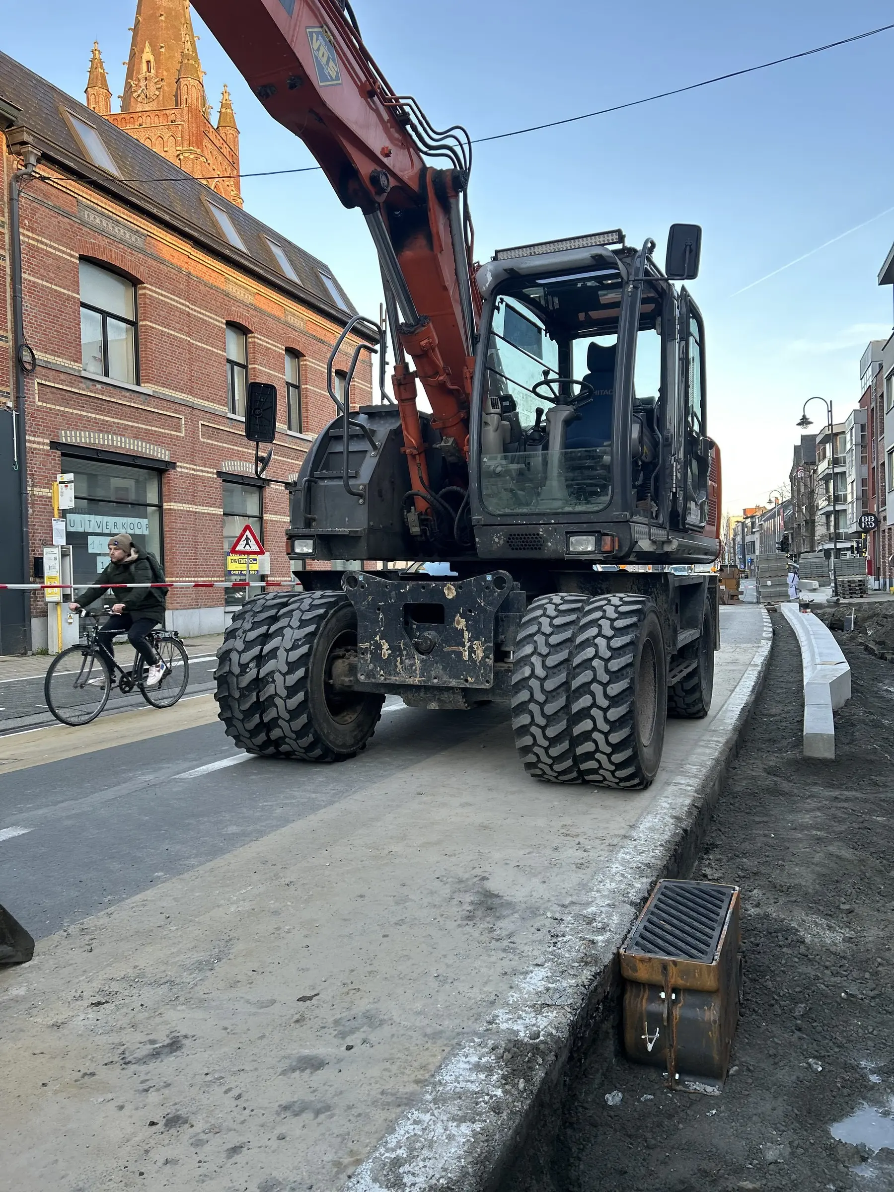 Mobiele graafmachine naast nieuwe boordstenen in het dorp