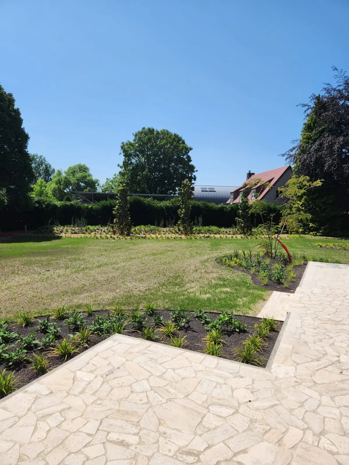 Natuursteen terras langs borders en gazon