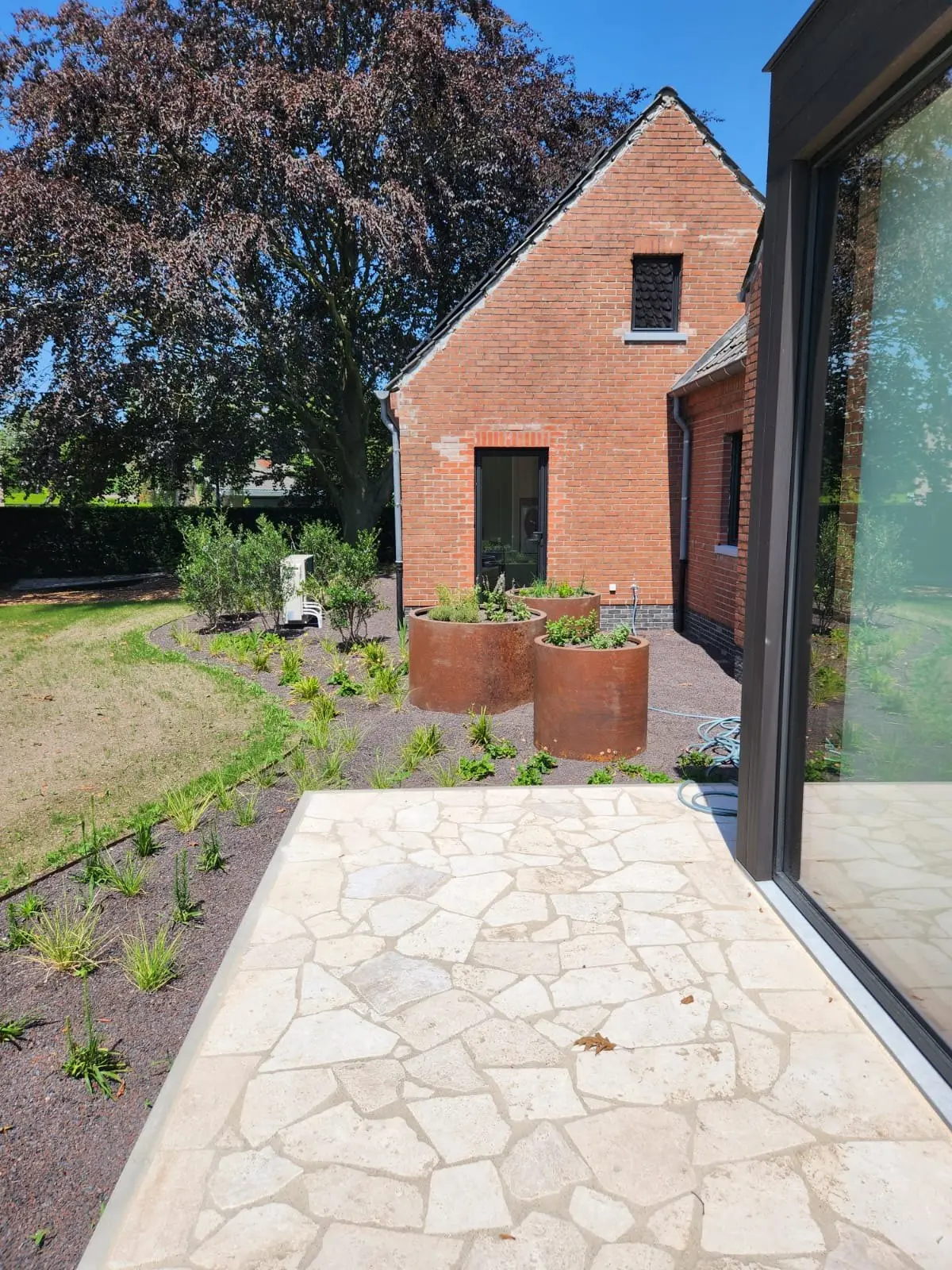 Terras met cortenbakken langs de gevel van de villa