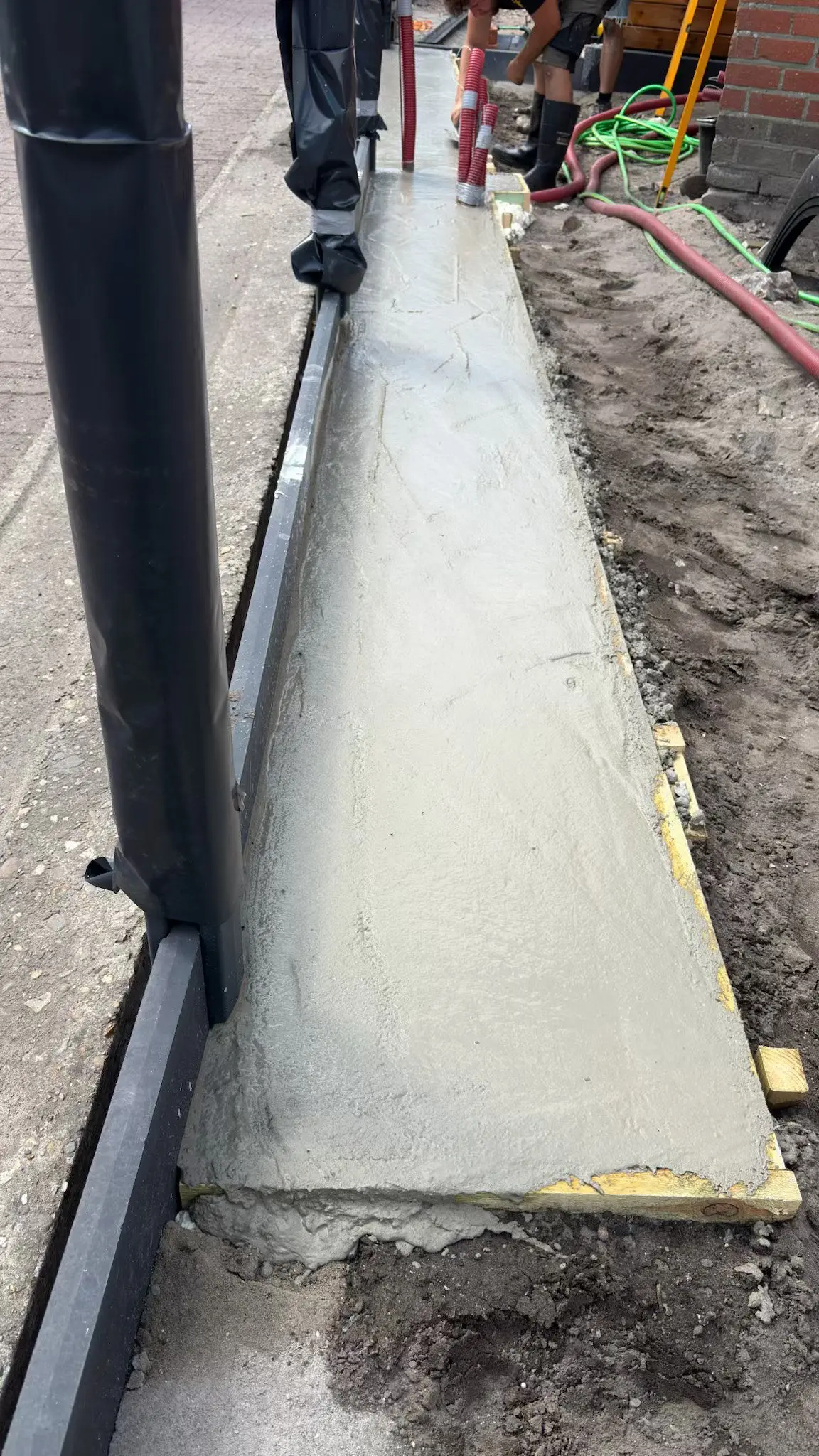 Pas gegoten betonstrook langs een paal