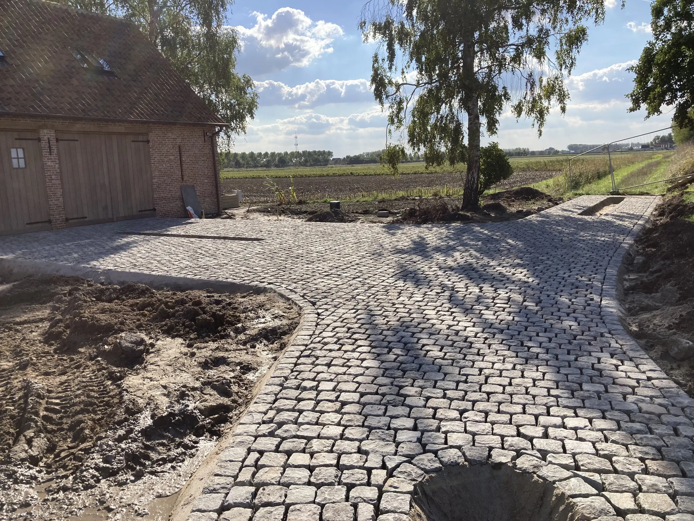 Bochtige oprit in kasseien bij de garage tijdens de aanleg