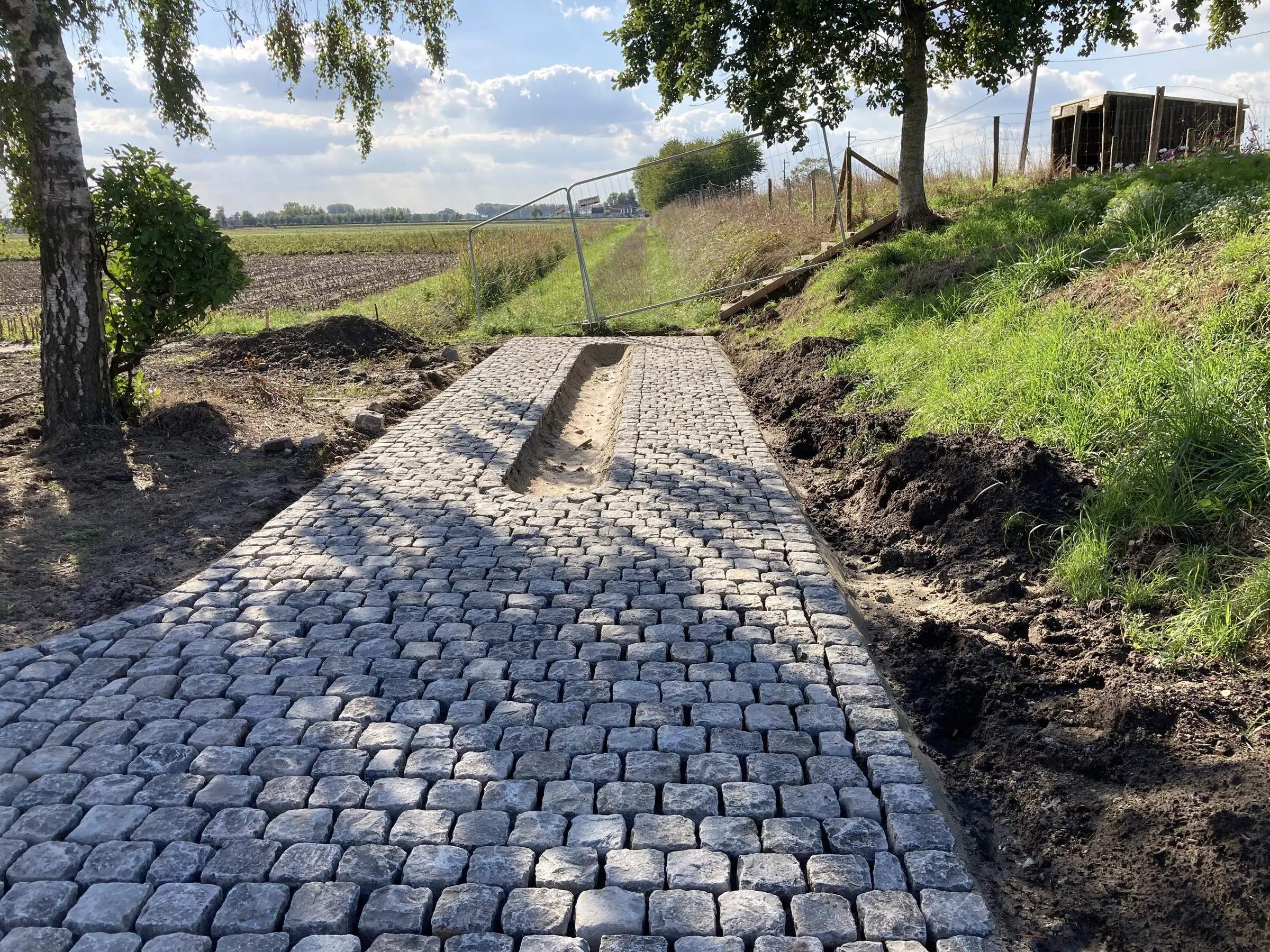 Smal kasseipad met een geul, langs een grashelling