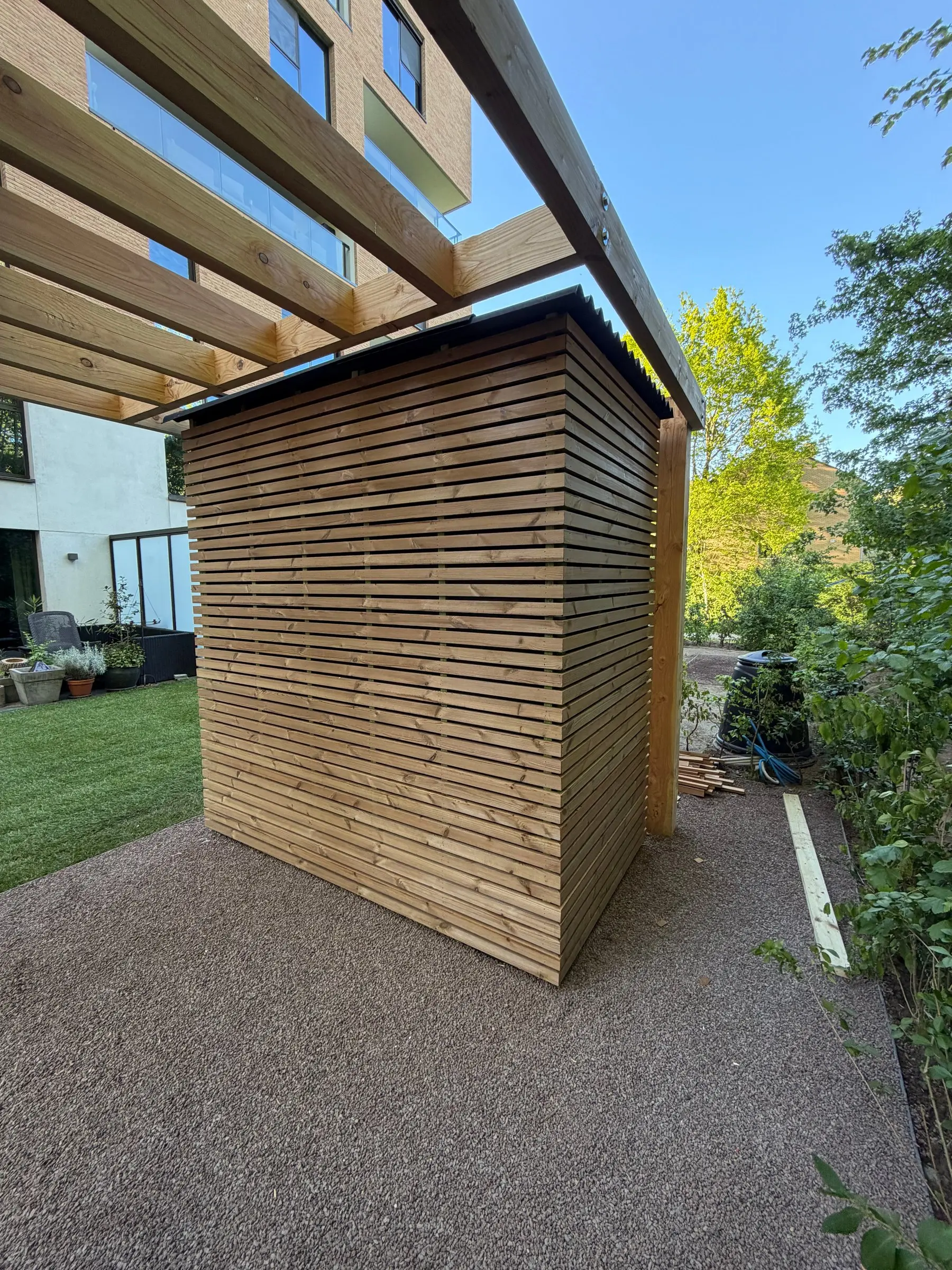 Tuinhuis met latbekleding en pergola langs het gras